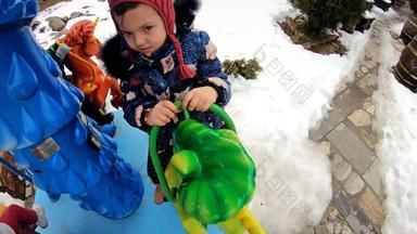 快乐女孩享受骑旋转木马在户外冬天雪可爱的蹒跚学步的孩子有趣的游乐场家庭孩子们支出一天娱乐公园慢运动